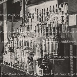 Black and white photograph of liquor bottles lined up behind a New Orleans bar, used as Anatomy of Release chapter art.
